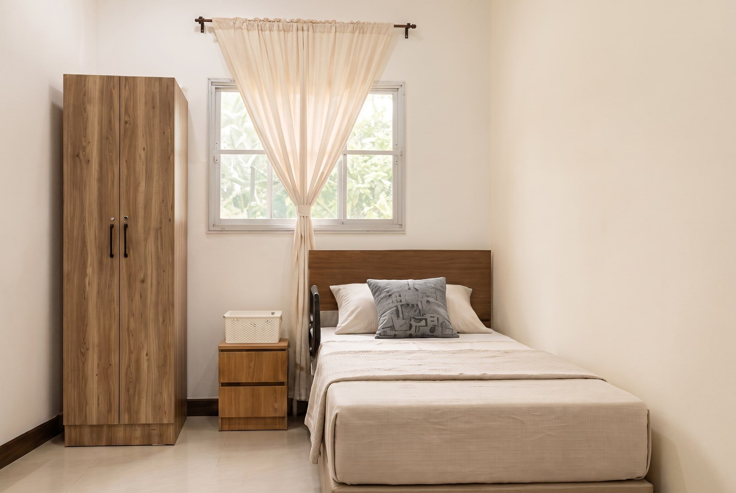 Renovated bedroom corner with a made-up bed under a soft curtained window